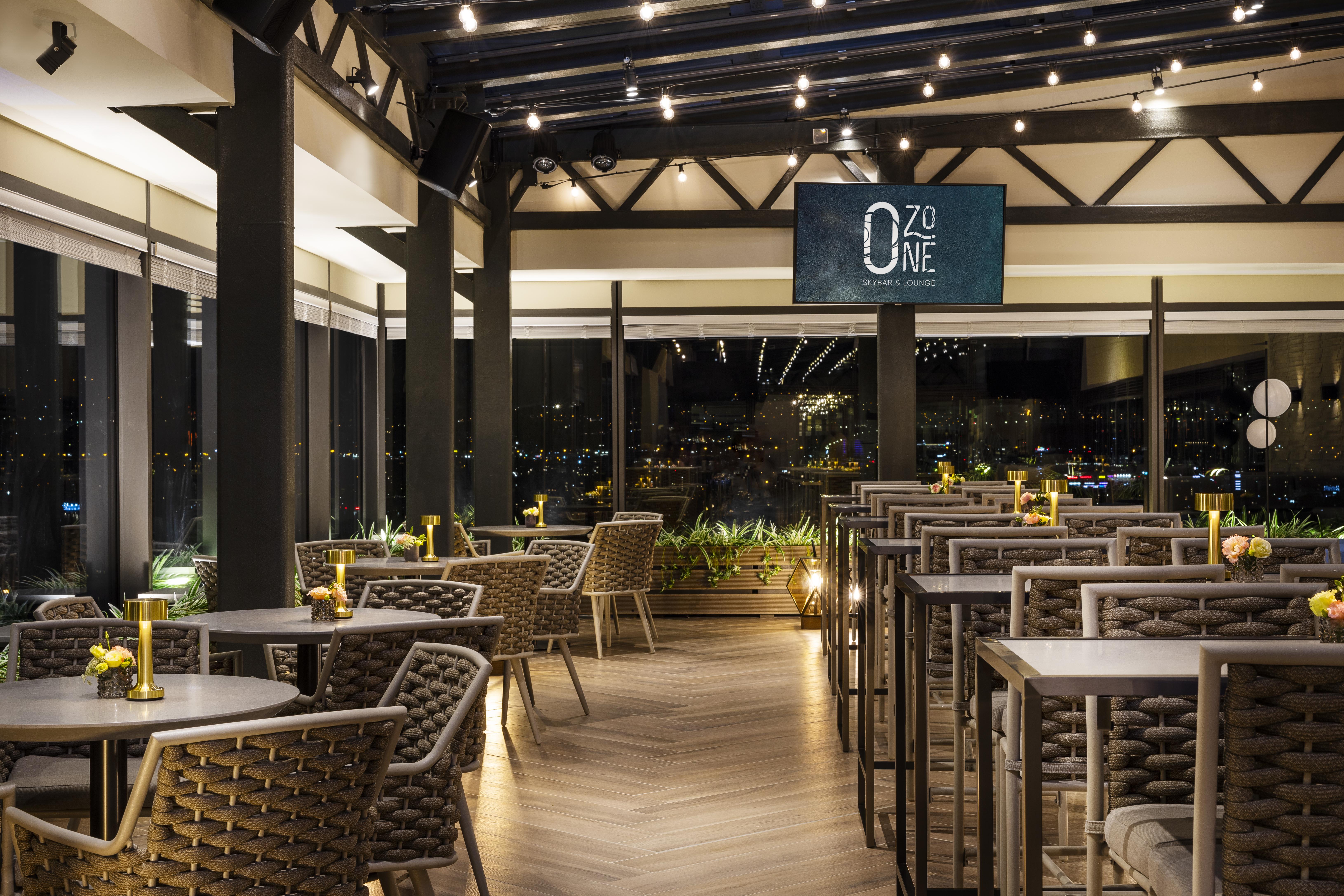 Grand Hotel Millennium โซเฟีย ภายนอก รูปภาพ The photo depicts a modern restaurant interior with a stylish design. The space features a series of tables and chairs arranged neatly, with a clean and sophisticated aesthetic. The tables are set with small yellow flowers, adding a touch of color to